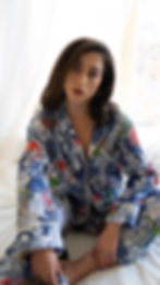 Thumbnail: Woman wearing tropical cotton pajama set, sitting on a bed in soft natural light.