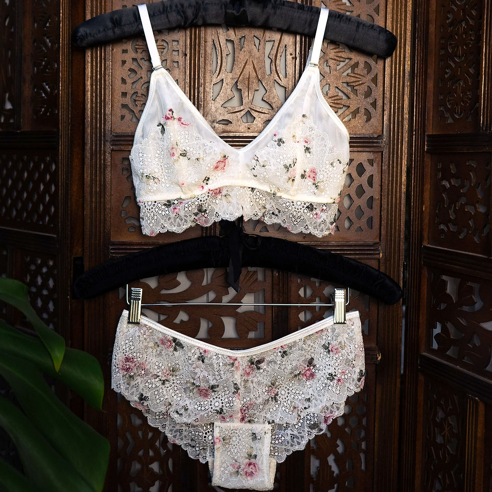 White lace lingerie set with pink floral embroidery, hanging on a carved wooden screen. Main Product photo