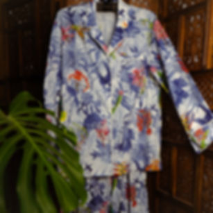 Tropical print cotton pajama set with button-down top and pants, hanging on a carved wooden screen.