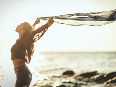 Woman holding a piece of fabric against the wind feeling whole