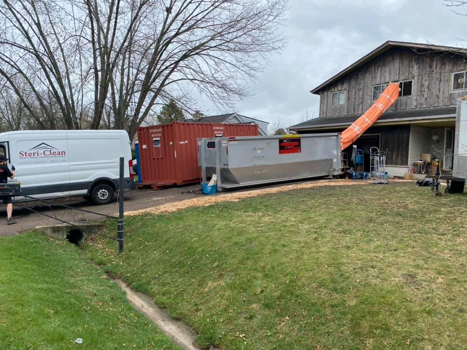 Steri-Clean crews secure a debris chute from a second story window to a 40 yard roll off to safely and quickly remove thousands of books from the second floor