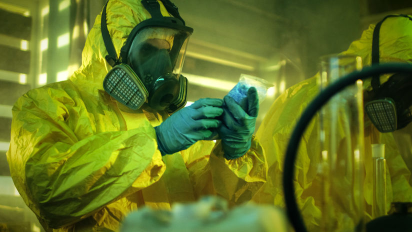 Two men in hazmat suits and respirators are working in an illegal meth lab