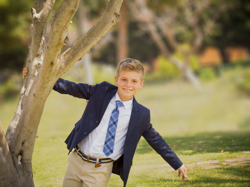 fresh portrait of a boy dressed in a suit and tie in a park for a special event like a com