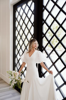 Bride with modern short blonde half-up braided hairstyle and striking red lipstick soft glam look.