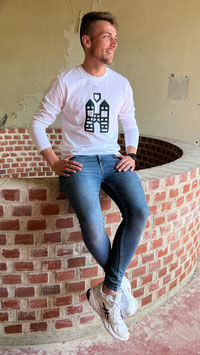 Miniaturbild: Ein junger Mann sitzt auf einer Backstein-Mauer. Er trägt ein Trigema Longsleeve in weiß. Das Shirt hat einen Brustaufdruck: Den Hachenburger Turm in grün. 