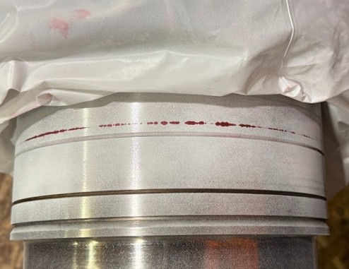 Red liquid penetrant indication of a circumferential crack on a machined generator component