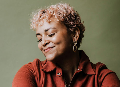 woman in a red shirt with green background smiling with her eyes closed