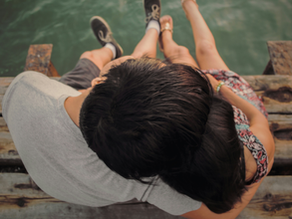 couple sitting my the water hugging