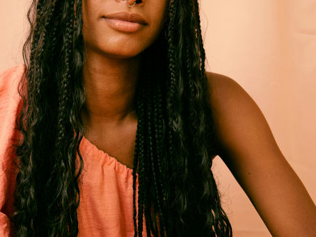 strong black woman posing in front of orange background
