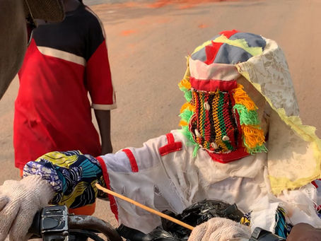 Egungun masquerade representing ancestral spirits interacting with the community in a Yoruba town