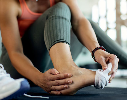 Woman in gym pulling off sock. Grabbing ankle and heel.