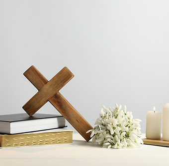 Burning church candles, wooden cross, ecclesiastical books and flowers on white table.jpg