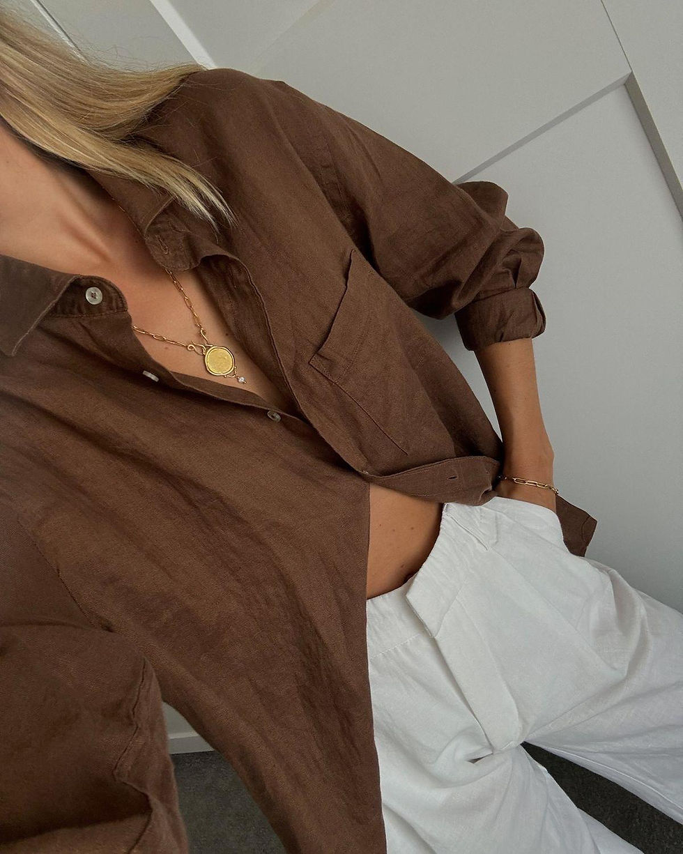 Woman in brown linen button-down shirt with gold necklace
