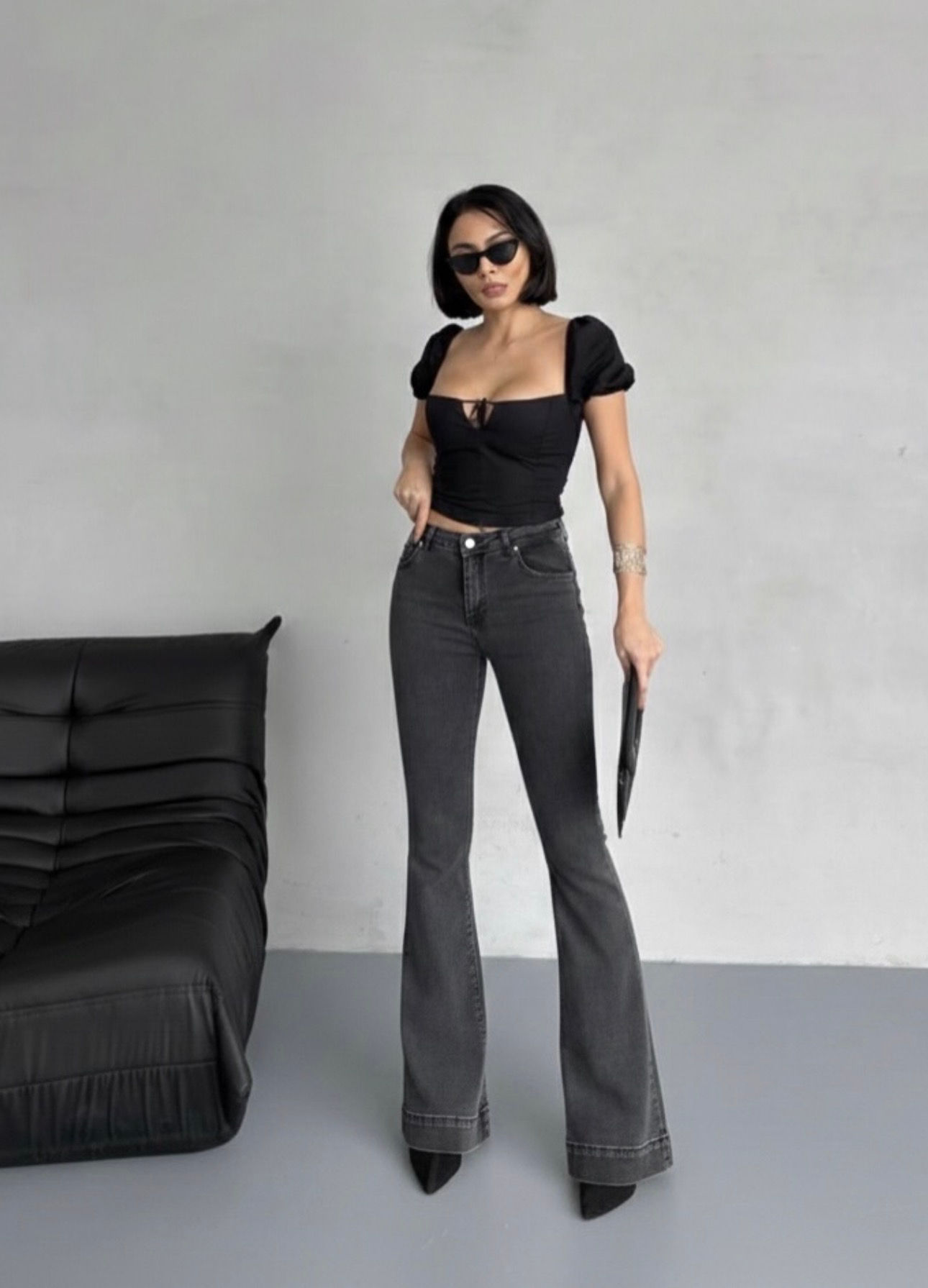 Woman in black square-neck crop top and dark flared jeans