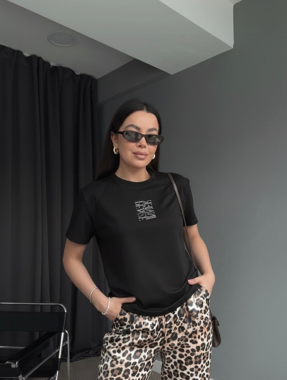 Woman in black t-shirt, sunglasses, leopard pants