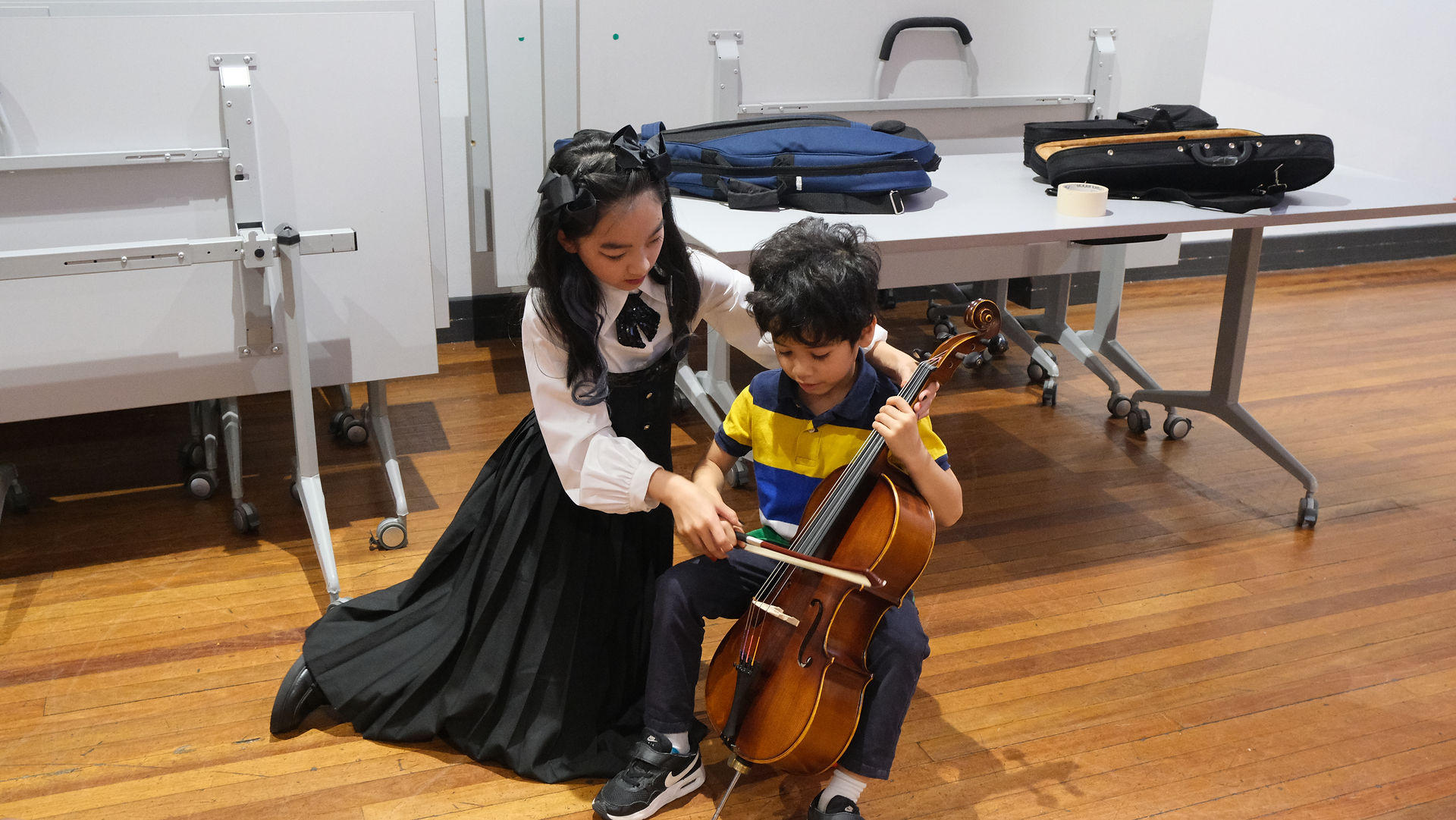 Alexandra guiding a little boy as he tries a cello for the first time
