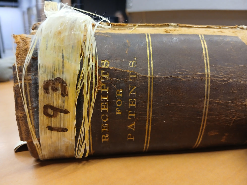 Close-up of an old, worn book titled "Receipts for Patents" with visible binding tape marked "193" on a wooden table.