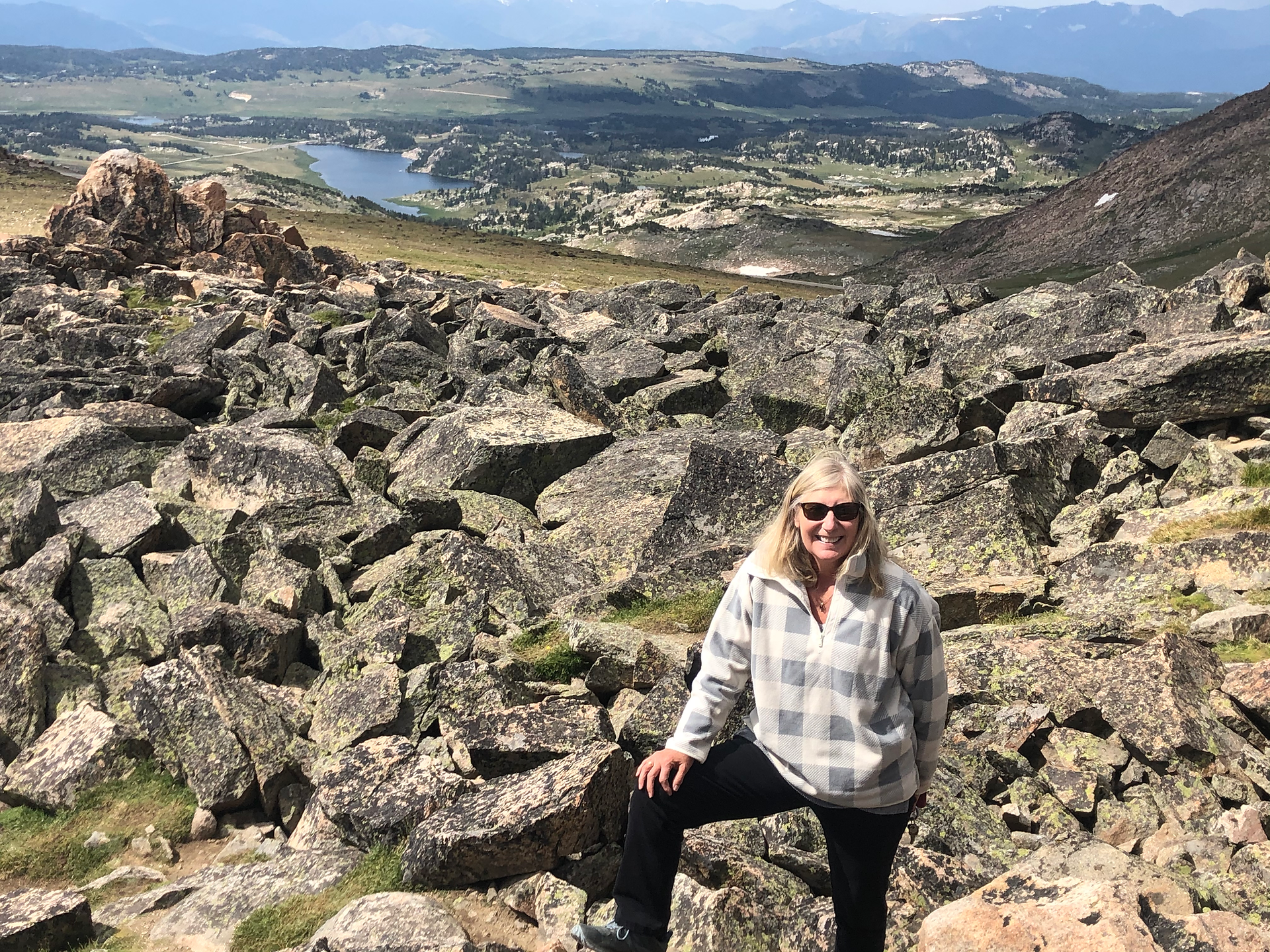 A woman ontop of a rocky hike looking triumphant