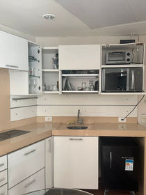 Foto de uma bancada de cozinha equipada com diversos utensílios, fogão, micro-ondas, frigobar.