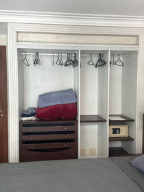 Guarda roupa com cabides, gavetas e pequeno cofre.