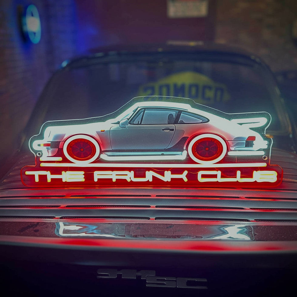 Close-up of the neon sign inside the car’s trunk, showing a glowing stylized car outline and “THE TRUNK CLUB” text.