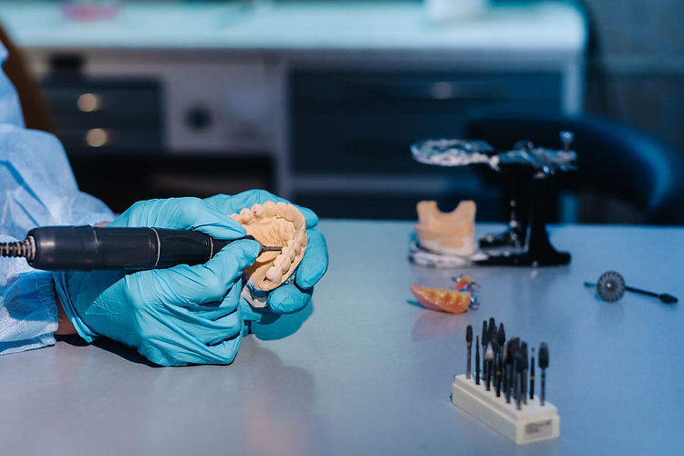 masked-gloved-dental-technician-works-prosthetic-tooth-his-lab.jpg