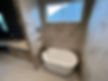 Concrete overlay wall in open rain shower with in shower tub. Matching concrete overlay on wedge shaped double basin vanity and lower makeup table.