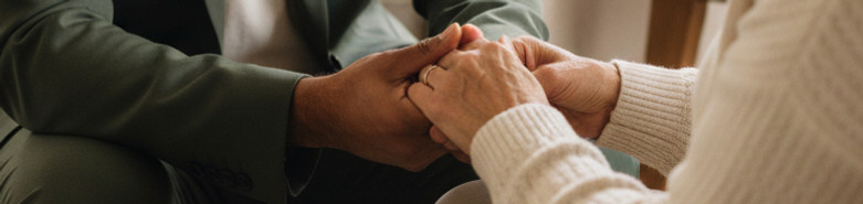 A close up of a physician holding hands with a patient during a home visit