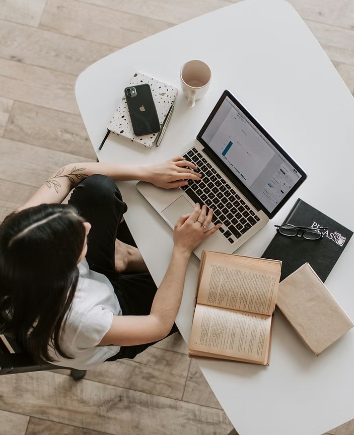 Designer working on a laptop at a white desk