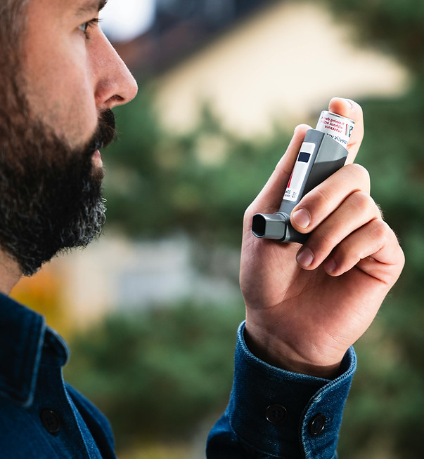 Adult male ready to adminster is inhaler for respiratory symptoms.