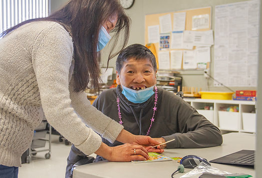 A man and a women, look at a greeting card. The man is smiling at the camera. 