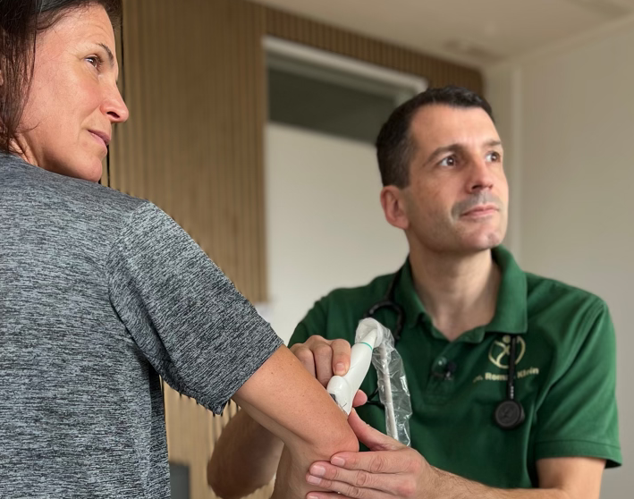 Arzt untersucht Patientenarm mit medizinischem Gerät