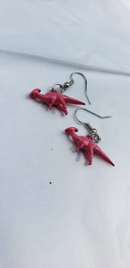 pink dinosaur earrings on white background