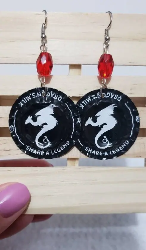 black and white beer cap earrings with image of dragon and red bead