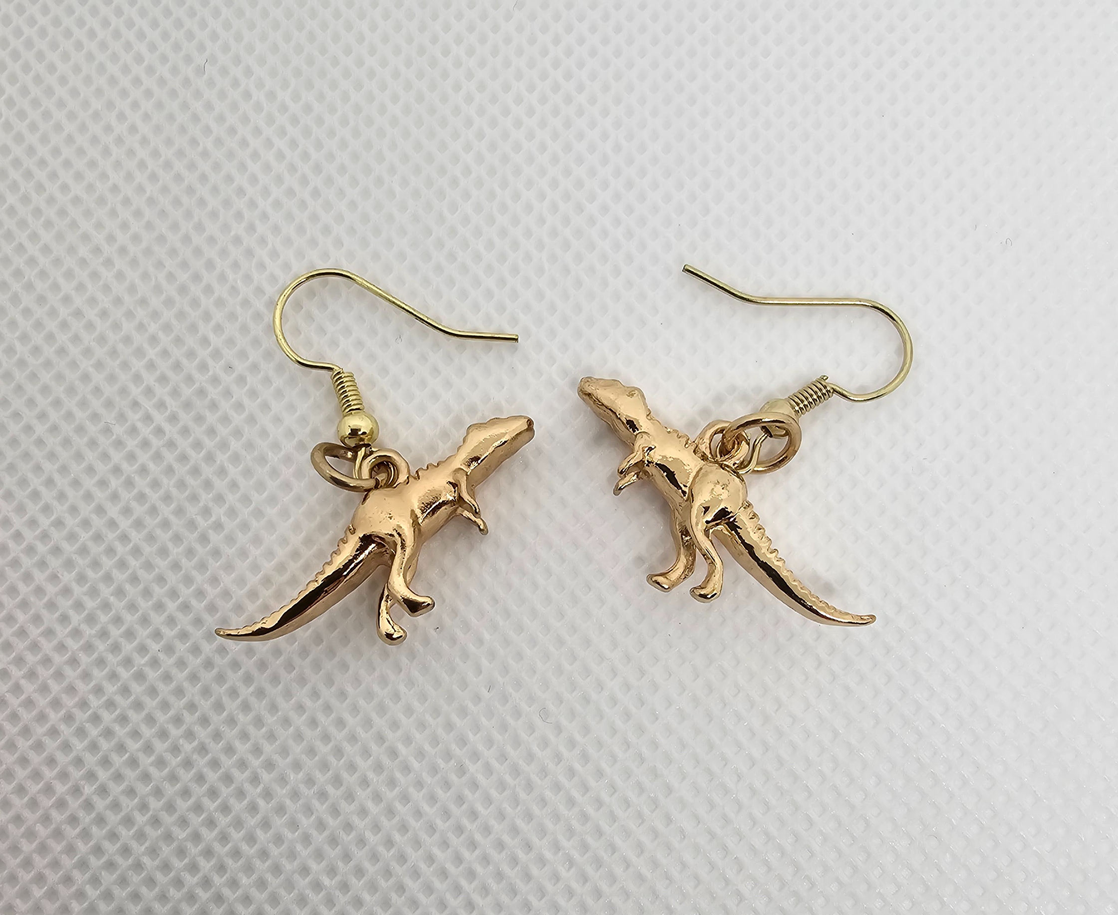 Tyrannosaurus rex dinosaur earrings laying down view