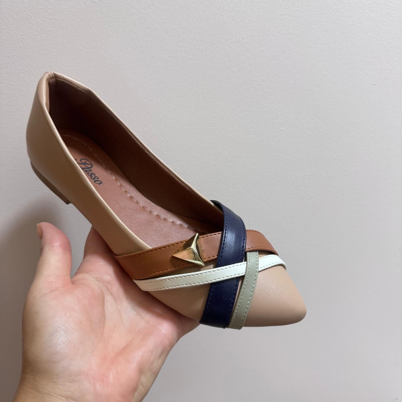 Alguém segurando um sapato nude com detalhes em várias cores, Sapatilha Milleny.