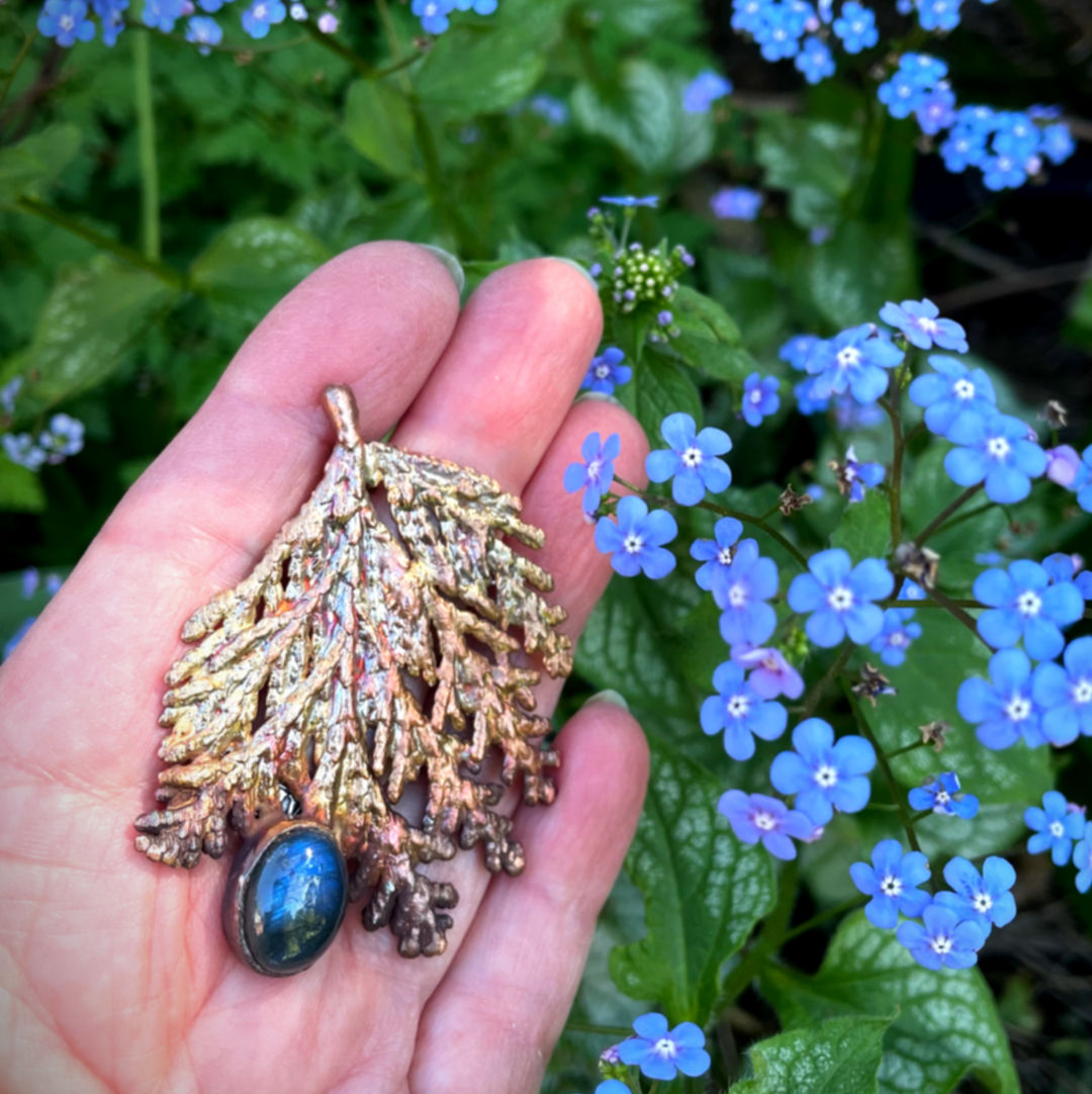 Hand holding Nature leaf pendant with blue labradorite