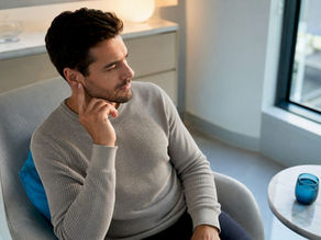 Adult gently touching outer ear in clinic