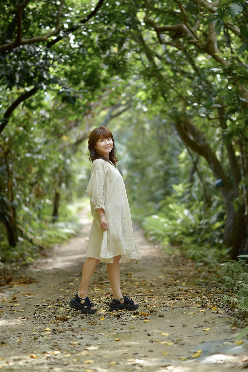 西表島の森で緑のトンネルで振り返る女性のロケーションポートレート写真