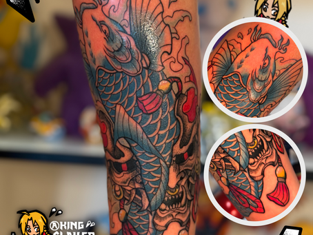 Japanese traditional tattoo featuring a blue koi fish swimming upward through a black and grey stipple-shaded Oni mask, symbolizing strength overcoming darkness.