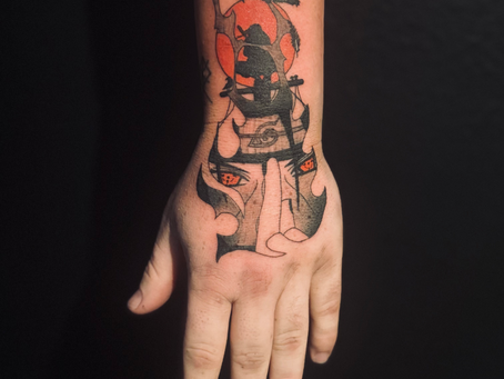 Black and grey Itachi hand tattoo featuring detailed linework and shading, capturing his iconic jutsu pose and the symbolic depth of his character from Naruto.