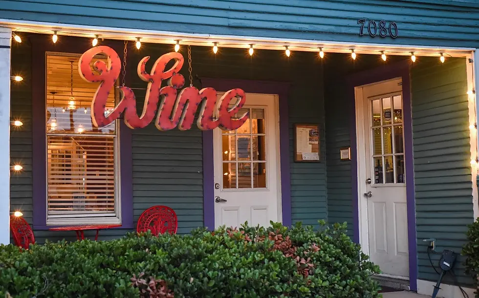 Exterior of Eight11 Place in Frisco with “Wine” sign and string lights.