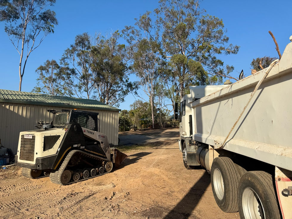 Track loader and dump truck at a landscaping site