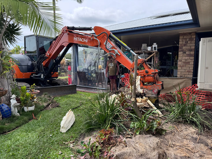 Excavator removing green waste from a garden