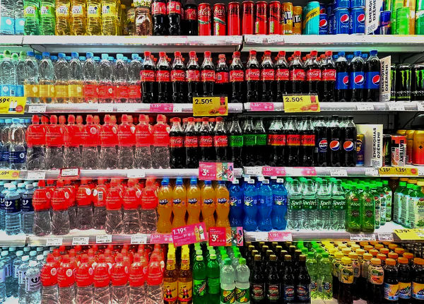 Supermarket shelves stocked with various bottled soft drinks and water