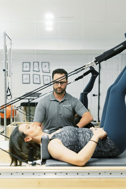 A patient performs a reformer exercise under the guidance of a licensed physiotherapist