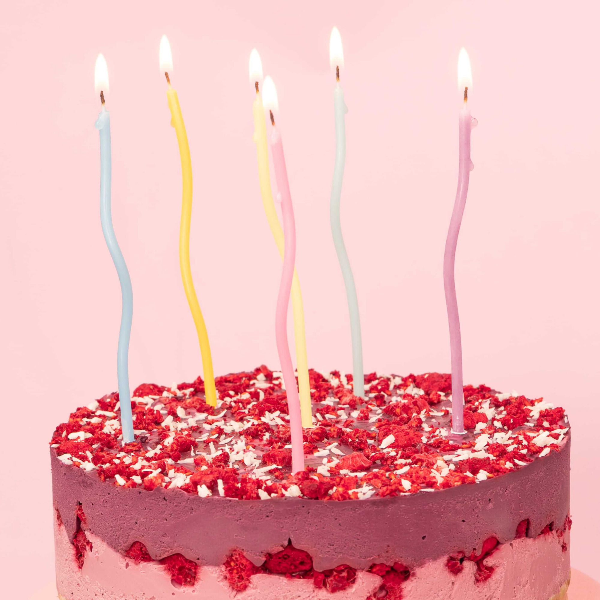 Pastell-bunte Kerzen, metallic und in Wellenlinien geschwungen, in einer Torte.