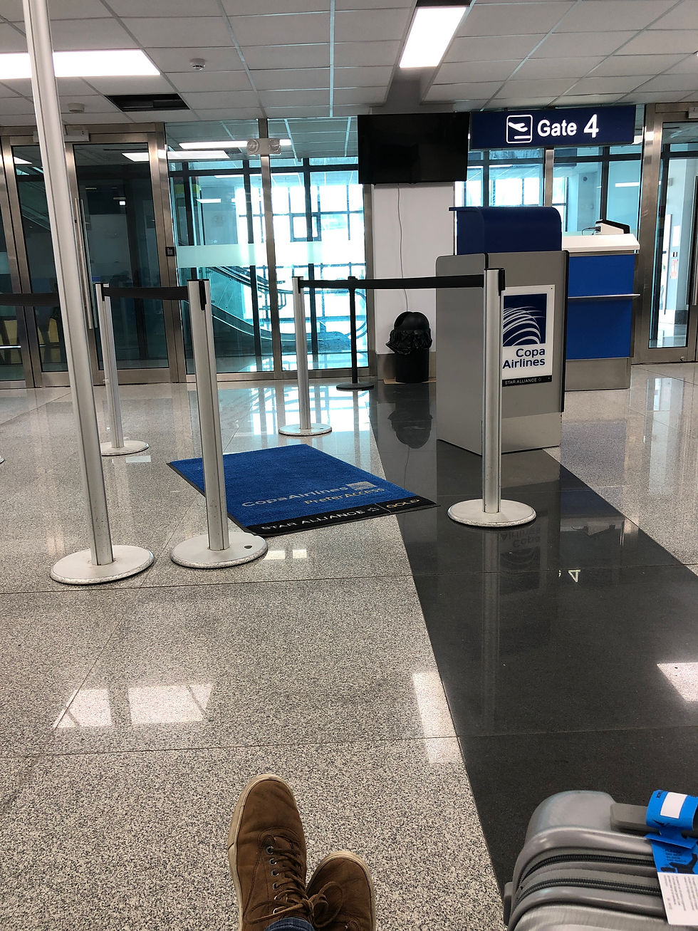 A nearly empty Copa Airlines gate at the Georgetown, Guyana airport, with only one traveler sitting with luggage visible in the foreground.