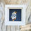 Thumbnail: Little puffin in white jumper with blue stripes and navy beannie on deep navy background white frame
