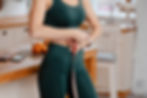 Cropped view of the sporty woman measuring waist with tape at bright kitchen. Weight loss